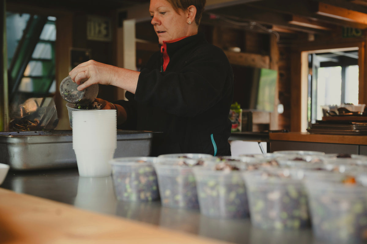 Heidi Finley portioning salad by hand into takeaway containers in the Maven Meals kitchen in SeaTac