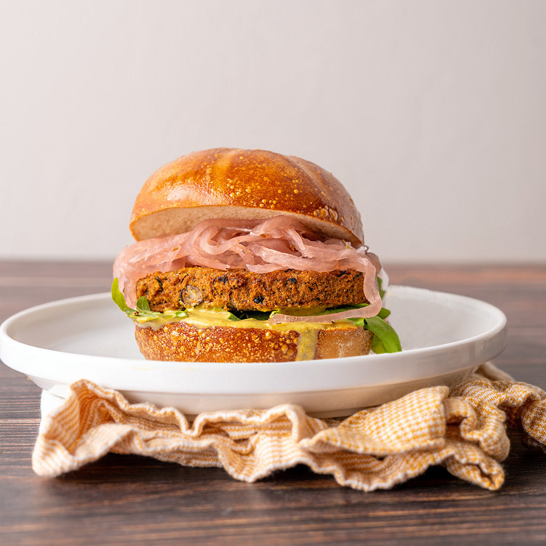 A vegetarian burger with black bean and quinoa patties, served on a bun with lettuce and tomato slices.