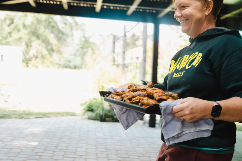 Heidi with a tray of chicken in the Maven Meals kitchen