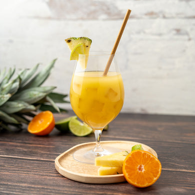 A glass of Mai Tai Mocktail garnished with a pineapple slice and served with a straw, accompanied by slices of orange and pineapple in the background.