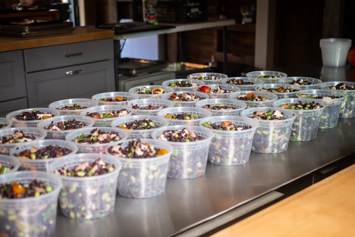 Dozens of Maven Meals dishes portioned into containers on the SeaTac kitchen bench