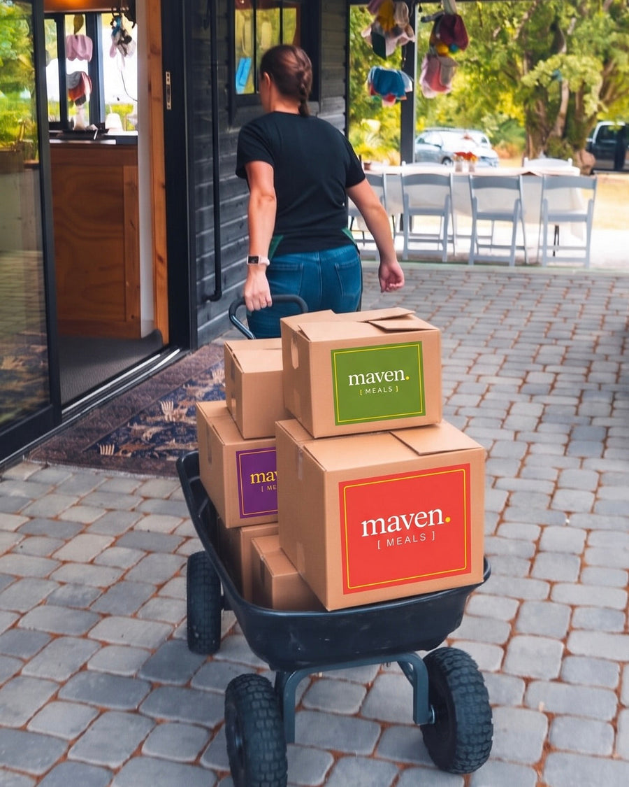 A cart stacked with branded Maven Meals boxes being wheeled to a customer's door